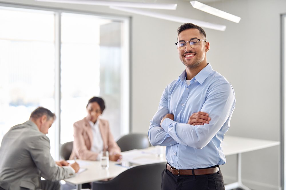 smiling young latin business man manager standing at office meeting. portrait