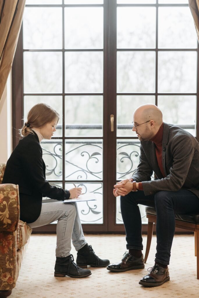 Two adults sitting by a window engaged in a professional conversation.